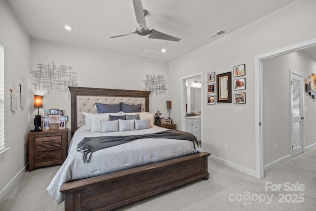 bedroom featuring light carpet, ensuite bath, and ceiling fan