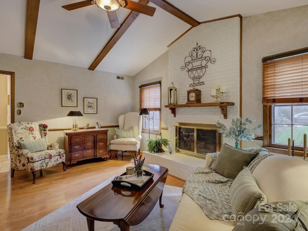 living room featuring light wood-type flooring, a fireplace, and beam ceiling