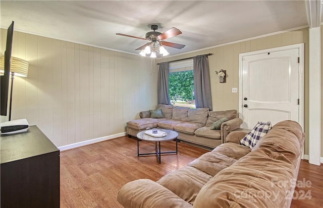 living room featuring ornamental molding, wood walls, ceiling fan, and hardwood / wood-style floors