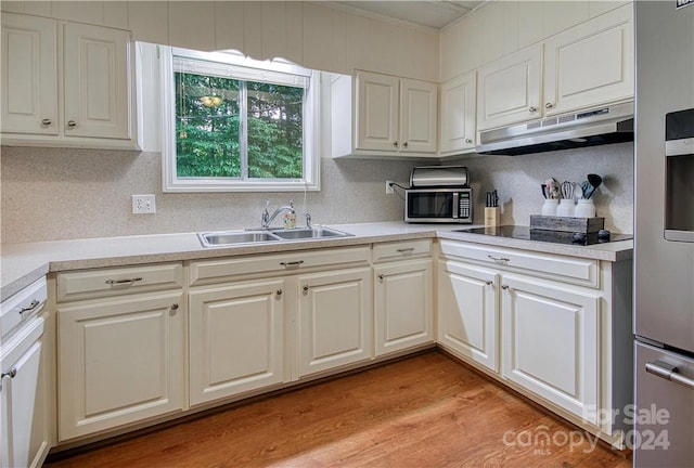 kitchen featuring light hardwood / wood-style floors, sink, white cabinets, decorative backsplash, and black electric cooktop