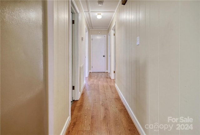 corridor with light hardwood / wood-style floors and wood walls