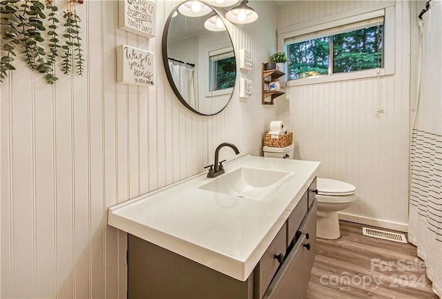 bathroom with wooden walls, hardwood / wood-style flooring, vanity, and toilet