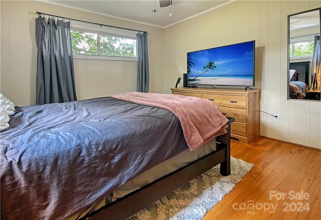 bedroom featuring wooden walls, ornamental molding, hardwood / wood-style floors, and ceiling fan