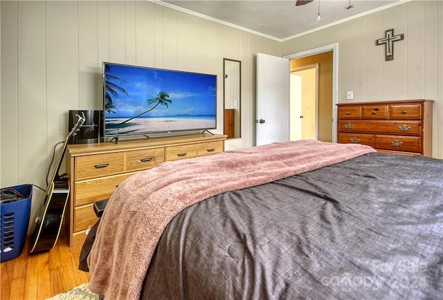 bedroom with wooden walls, ornamental molding, hardwood / wood-style floors, and ceiling fan