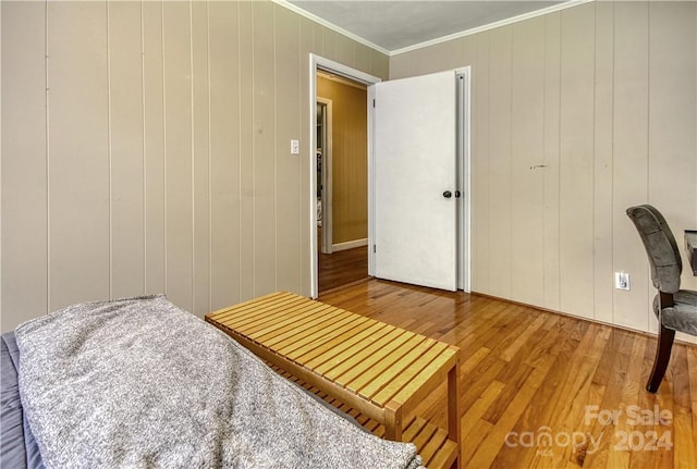 bedroom featuring wood-type flooring, wood walls, and ornamental molding