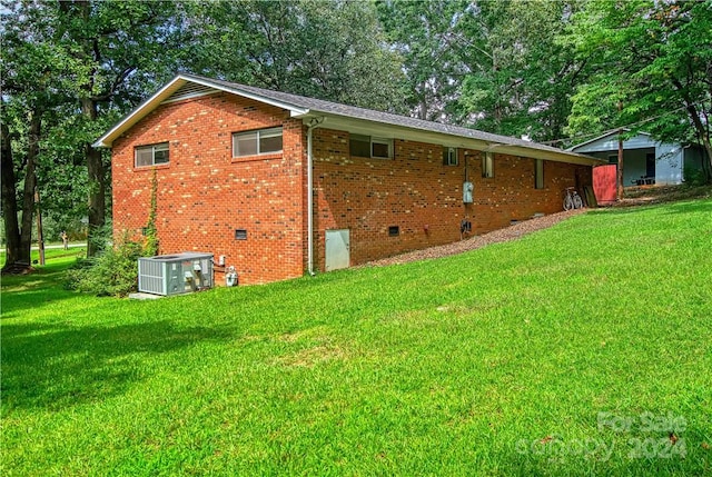 view of side of property with central AC unit and a yard