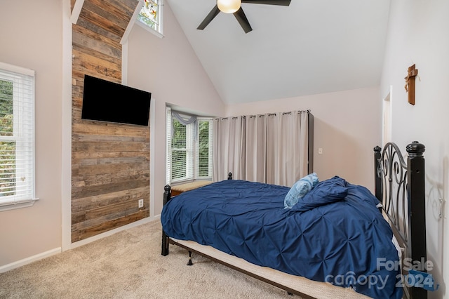 bedroom featuring ceiling fan, wooden walls, multiple windows, and high vaulted ceiling