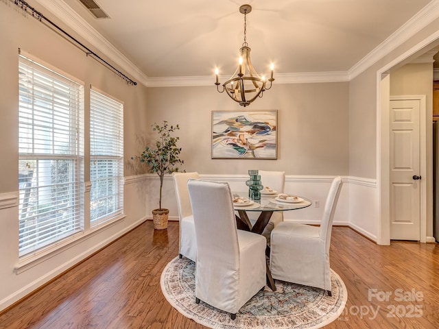 dining area featuring crown molding, an inviting chandelier, and hardwood / wood-style floors