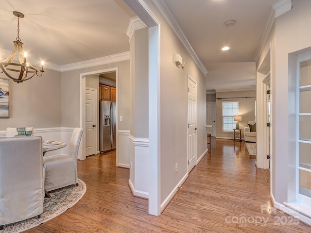 hallway featuring light hardwood / wood-style flooring, ornamental molding, and a chandelier