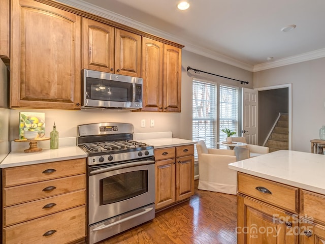 kitchen featuring stainless steel appliances, ornamental molding, and hardwood / wood-style floors