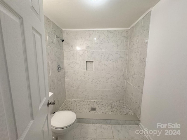 bathroom with tiled shower, ornamental molding, and toilet