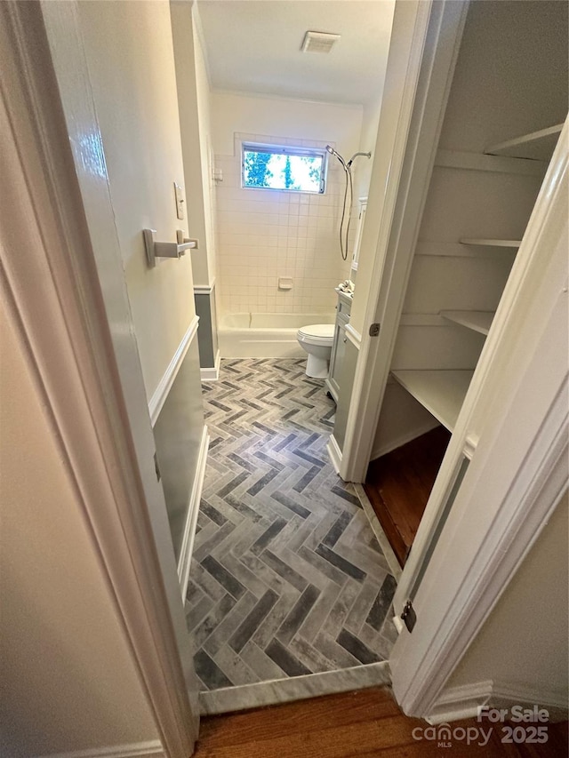 bathroom featuring toilet and tiled shower / bath