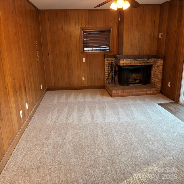 unfurnished living room with ceiling fan, light colored carpet, a fireplace, and wooden walls