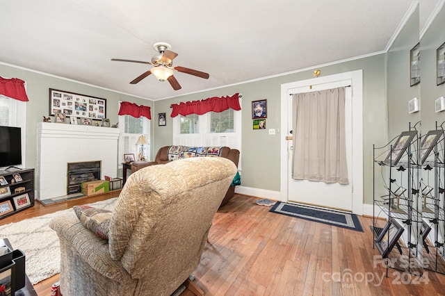 living room with crown molding, a fireplace, hardwood / wood-style floors, and ceiling fan