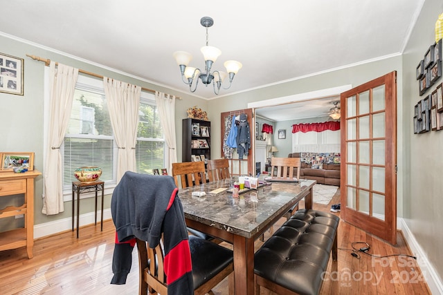 dining area with light wood-type flooring, ceiling fan with notable chandelier, and ornamental molding