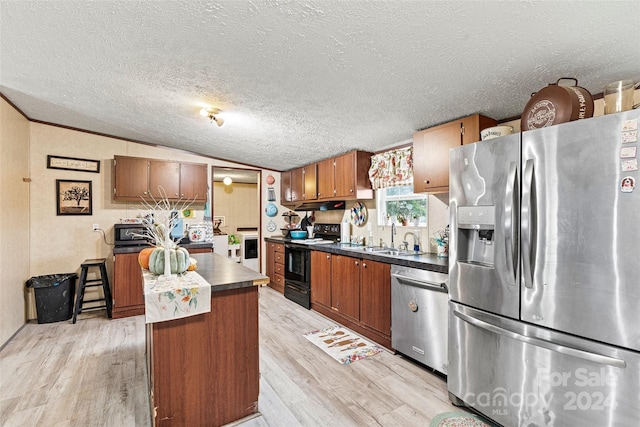 7686 Hickory Creek Dr, Denver, NC 28037 - kitchen with brown cabinetry, dark countertops, light wood-style floors, a sink, and appliances with stainless steel finishes