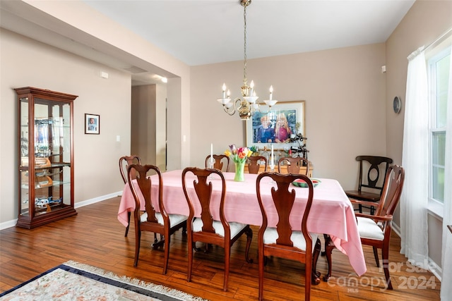 dining area with wood-type flooring and an inviting chandelier