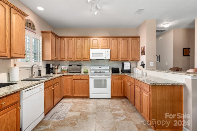 kitchen with kitchen peninsula, sink, white appliances, light stone countertops, and decorative backsplash