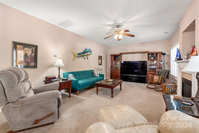 living room with a fireplace, ceiling fan, and light colored carpet