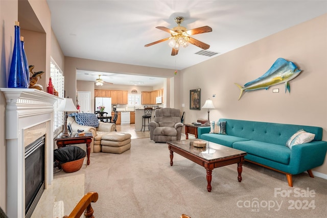 carpeted living room with ceiling fan and a high end fireplace