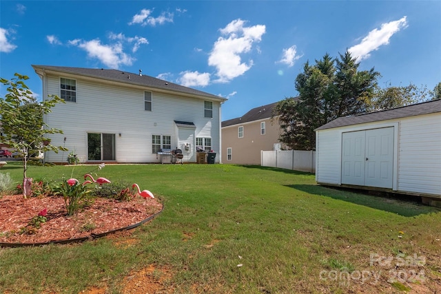 rear view of house featuring a yard and a storage unit