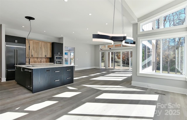 kitchen with dark wood-type flooring, hanging light fixtures, appliances with stainless steel finishes, and a kitchen island