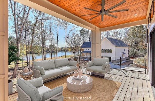 deck featuring ceiling fan, an outdoor living space, and a water view