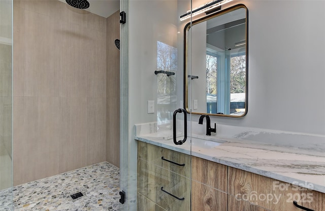 bathroom with tiled shower and vanity