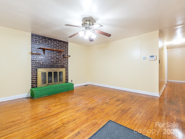 unfurnished living room with ceiling fan, a brick fireplace, and hardwood / wood-style floors