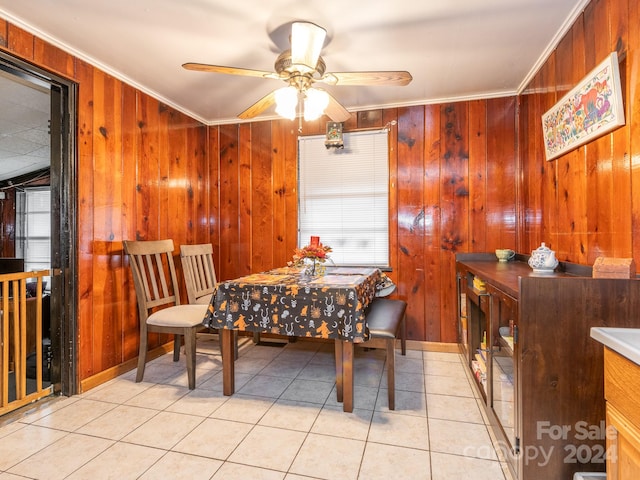 tiled dining area featuring ornamental molding, wooden walls, and ceiling fan