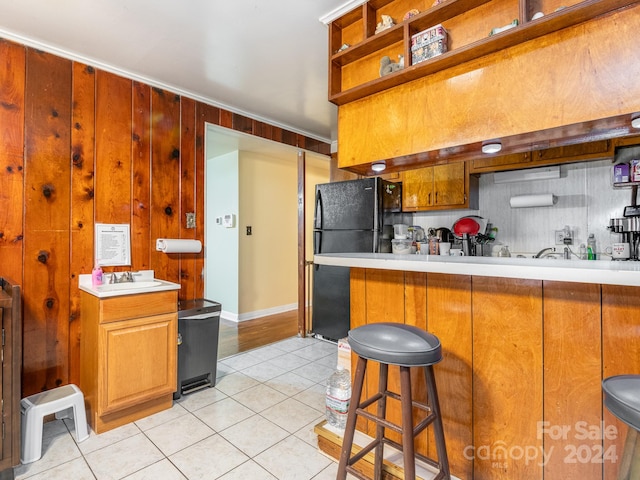 kitchen featuring a kitchen breakfast bar, black refrigerator, kitchen peninsula, and light tile patterned floors