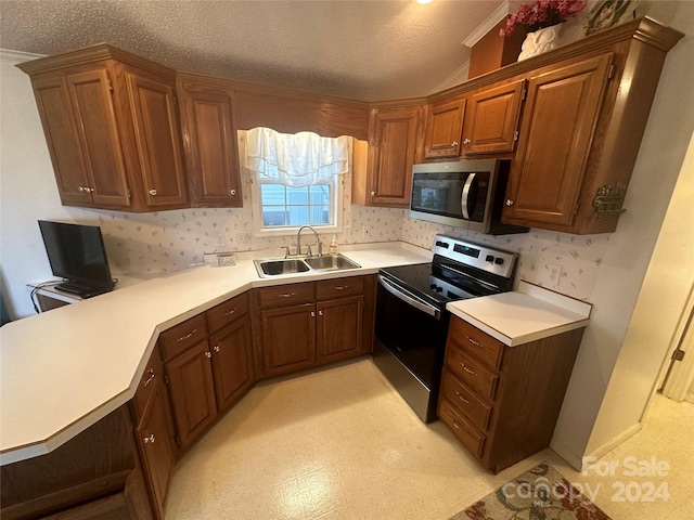 kitchen featuring stainless steel appliances, a textured ceiling, kitchen peninsula, and sink