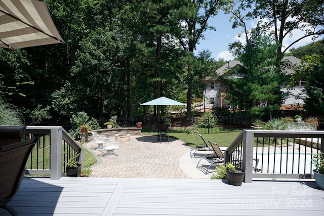 wooden deck featuring a swimming pool, a yard, a patio area, and an outdoor fire pit