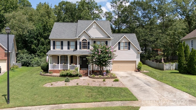 view of front of house featuring a front yard, cooling unit, a garage, and covered porch