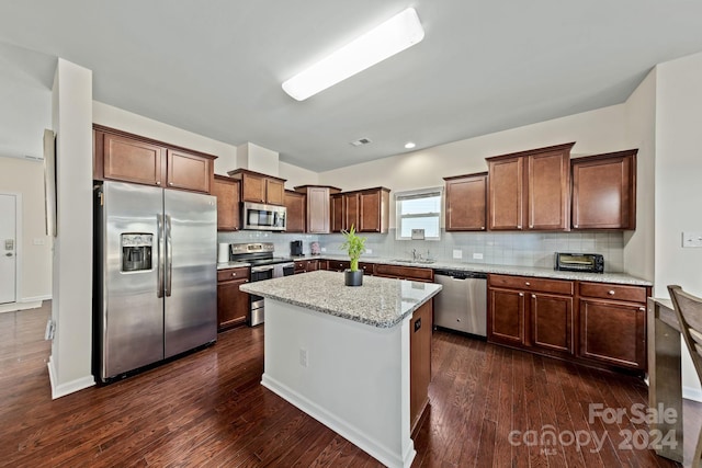 kitchen featuring sink, appliances with stainless steel finishes, a center island, light stone countertops, and dark hardwood / wood-style flooring