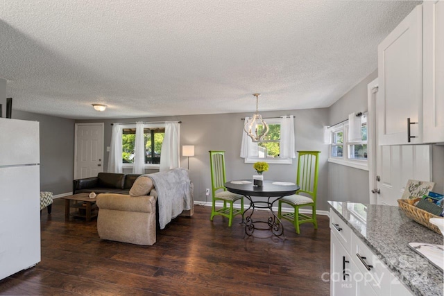 living room with a textured ceiling, plenty of natural light, and dark wood-type flooring