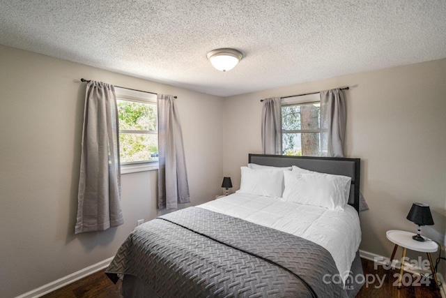 bedroom featuring wood-type flooring, multiple windows, and a textured ceiling