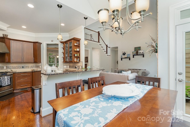 dining area with ornamental molding, an inviting chandelier, and dark wood-type flooring