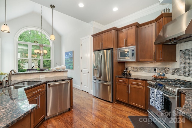 kitchen featuring sink, decorative light fixtures, wall chimney range hood, stainless steel appliances, and decorative backsplash