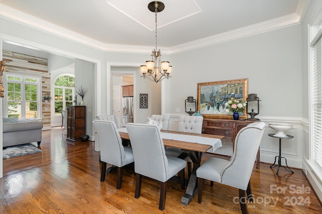 dining space with ornamental molding, an inviting chandelier, and hardwood / wood-style floors