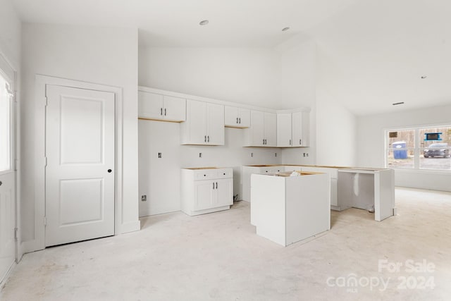 kitchen featuring a center island, white cabinets, and high vaulted ceiling