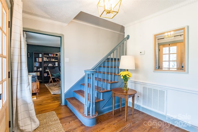 stairway featuring a textured ceiling, hardwood / wood-style floors, and crown molding