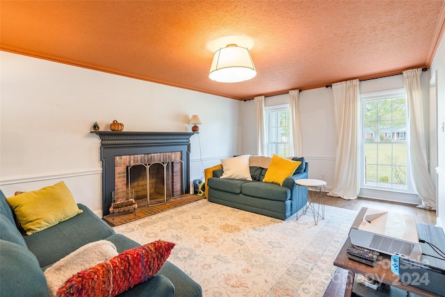 living room featuring a fireplace, wood-type flooring, a textured ceiling, and ornamental molding