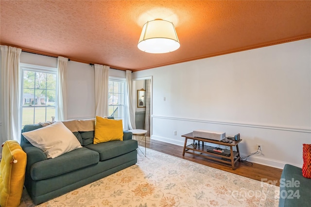 living room with a textured ceiling, hardwood / wood-style flooring, and crown molding