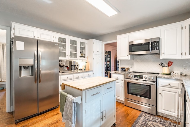 kitchen featuring stainless steel appliances, light hardwood / wood-style floors, white cabinetry, and butcher block counters