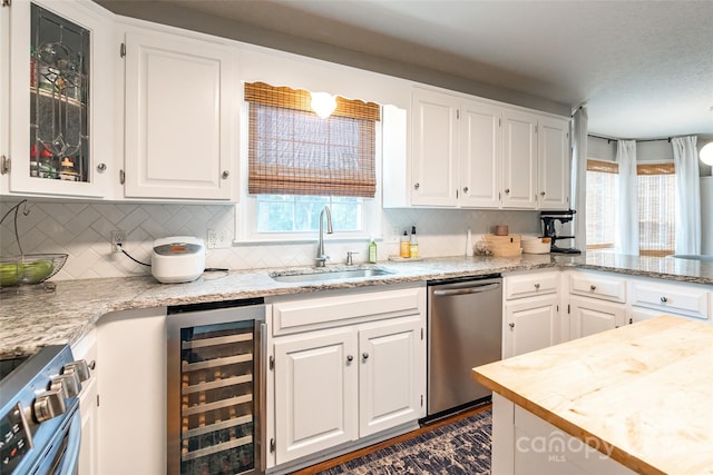 kitchen featuring white cabinets, beverage cooler, sink, and appliances with stainless steel finishes