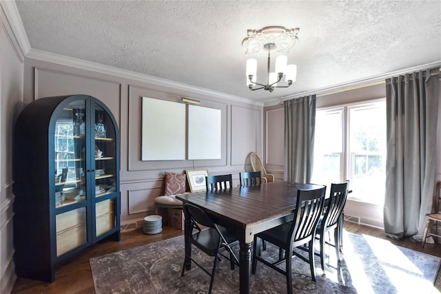 dining room with dark hardwood / wood-style flooring, an inviting chandelier, a textured ceiling, and crown molding