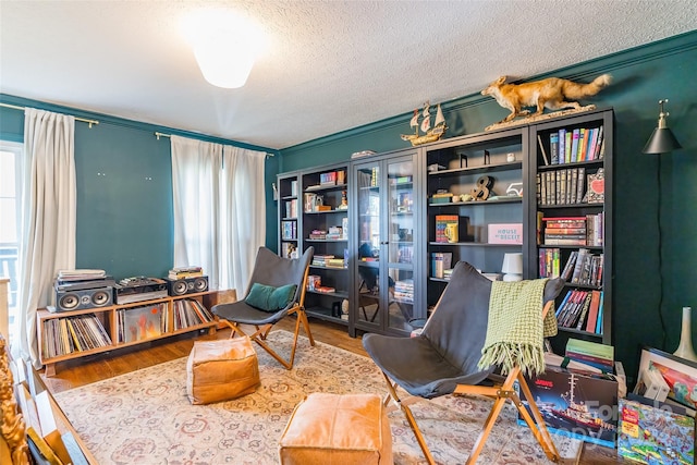 sitting room featuring wood-type flooring, a healthy amount of sunlight, and a textured ceiling