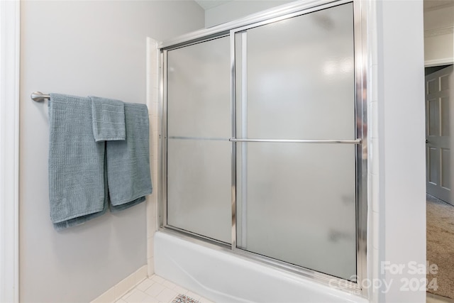 bathroom featuring tile patterned flooring and shower / bath combination with glass door