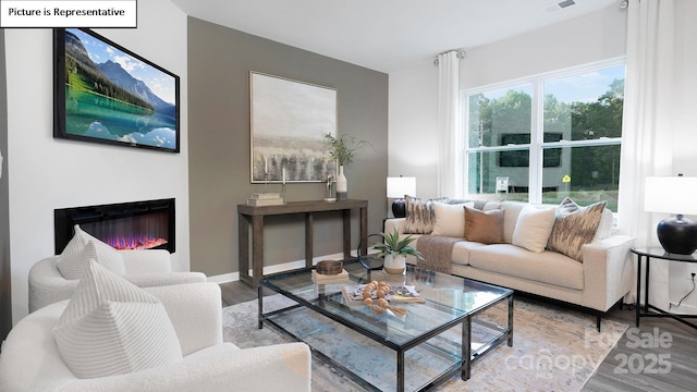 living room with baseboards, visible vents, wood finished floors, and a glass covered fireplace